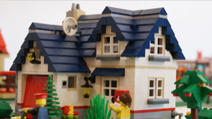 Ein charmantes LEGO-Dorfmotiv mit einem gemütlichen Haus, festlichen Bäumen und weihnachtlichen Dekorationen.