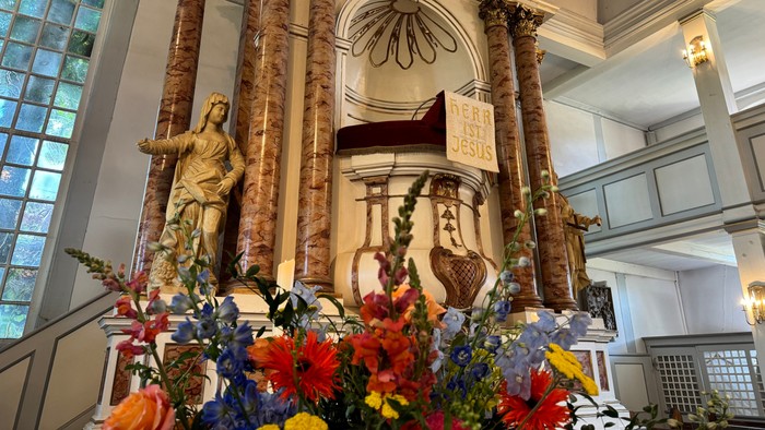 Eleganter Altar, geschmückt mit Statuen, verzierten Säulen und üppigen Blumenarrangements in einem prächtigen Kircheninnenraum.