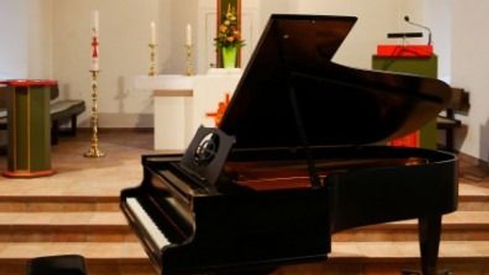 Elegante Kircheninnenausstattung mit einem Flügel, Altar und markanter Kreuzdekoration.