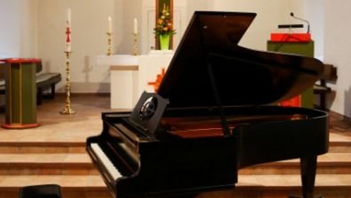Elegante Kircheninnenausstattung mit einem Flügel, Altar und markanter Kreuzdekoration.