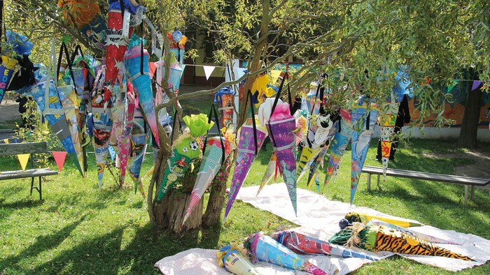 Bunte Drachen im Garten, einige auf Stangen, andere auf dem Boden
