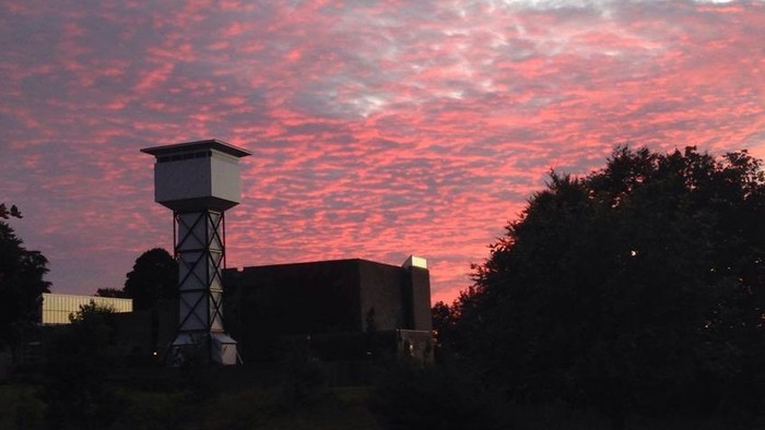 En aftenhimmel med lyserøde skyer over en kirkebygning og kirketårn.