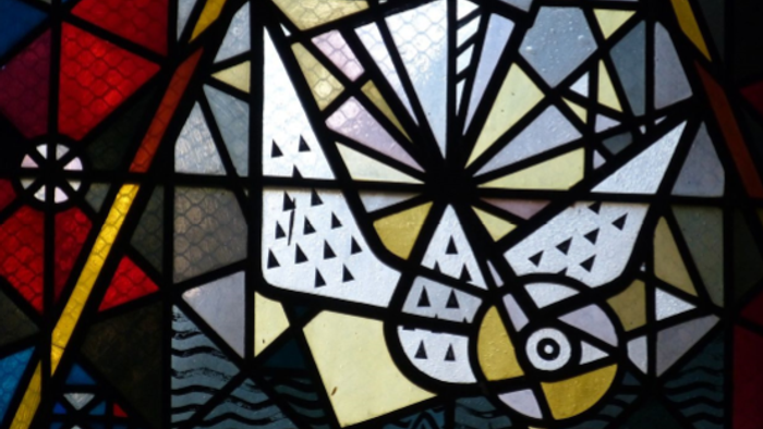 Buntglas-Kunst mit abstrakten geometrischen und organischen Formen in leuchtenden Farben und filigranen Mustern.
