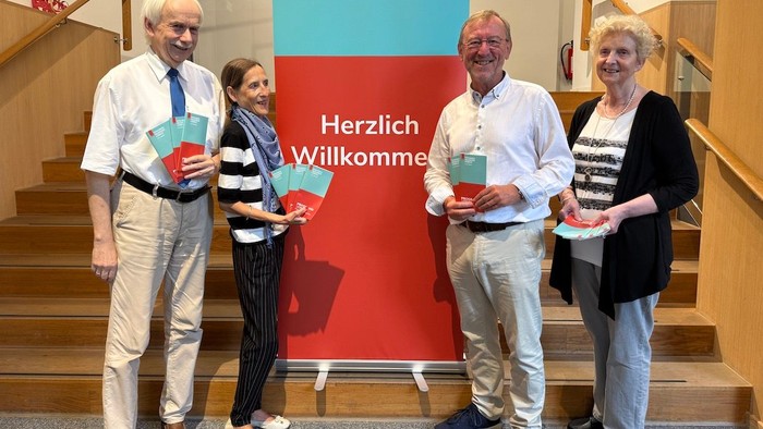 Zwei Männer und zwei Frauen stehen vor dem Roll Up der Seniorenakadmie und halten die Programmflyer in den Händen.