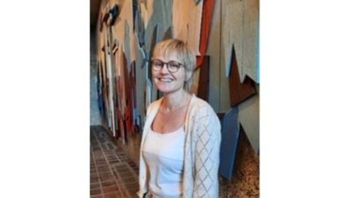 Foto af Lene F. Rasmussen, kort lyst hår briller med mørkt stel, hvid top og beige striktrøje 