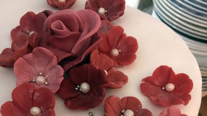 Rote und rosafarbene Blumen aus Zucker auf weißem Kuchen.