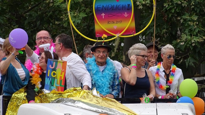 Eine Gruppe von Menschen feiert auf einem Auto, geschmückt mit Luftballons und bunten Accessoires.