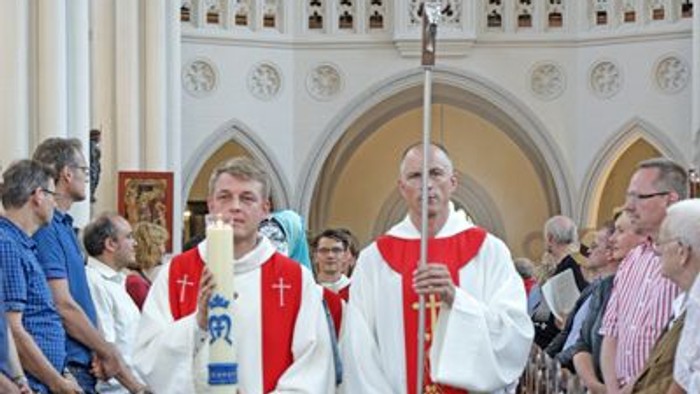 Zwei Priester in Kirchengewändern mit Kreuzprozession