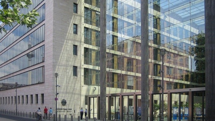Modernes Bürogebäude mit Glasfassade und Fußgängern auf dem Bürgersteig