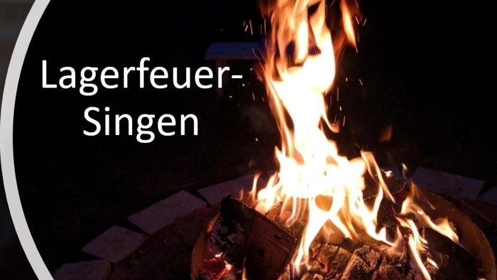 Ein Lagerfeuer mit hell lodernden Flammen, begleitet vom deutschen Ausdruck *„Lagerfeuer-Singen“*, der das Singen am Lagerfeuer bezeichnet.