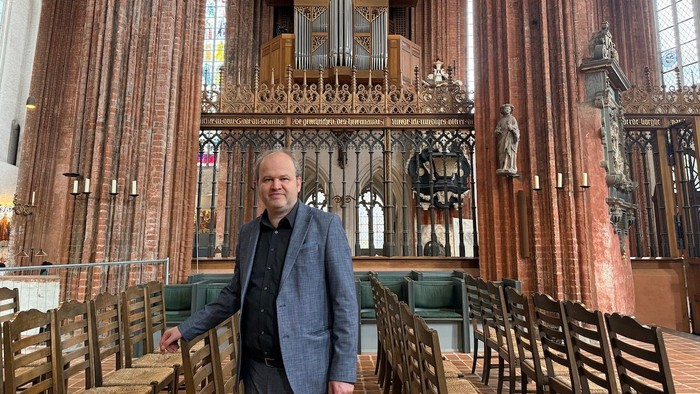Ein Mann steht in einer Kirche, eine Orgel ist im Hintergrund zu sehen.