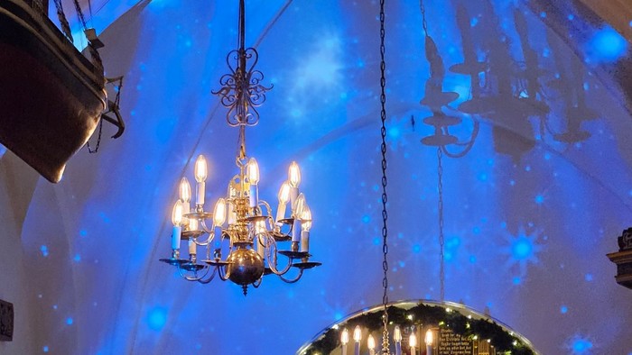 Religiøs ceremoni i en stor, blåoplyst kirke med præster, der synger, og prægtige dekorationer.
