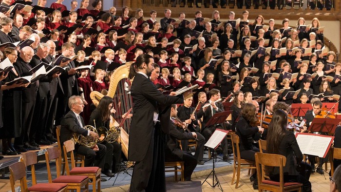 Ein großer Chor singt unter Leitung eines Dirigenten in einer Kirche