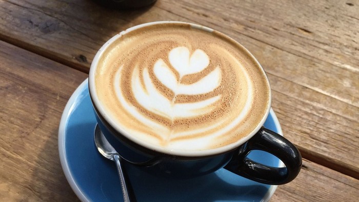 Eine Tasse Kaffee mit Milchschaumherz auf einem Holztisch