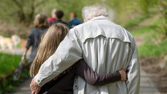 Ein Mädchen und ein alter Mann gehen Arm in Arm spazieren