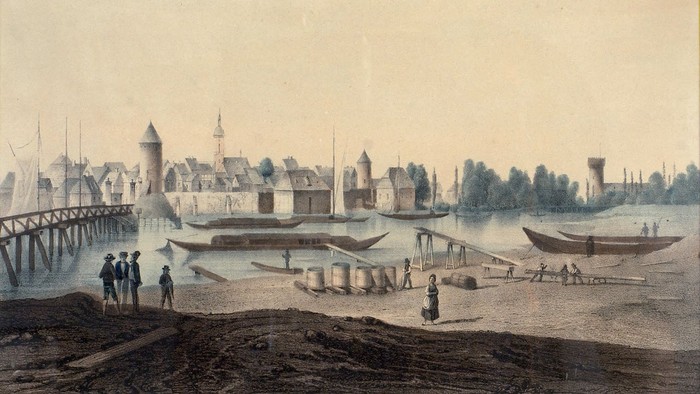 Das Bild zeigt eine historische Flusslandschaft mit Booten und Gebäuden.