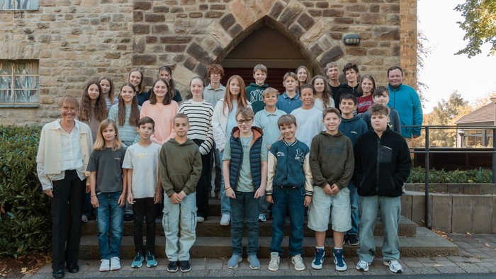 24 Konfikinder mit Teamer*innen und Pfarrerin vor dem Kirchenportal.