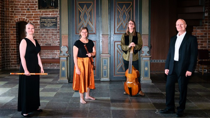 Et kvartet musikere i en historisk indendørsscene, hver med forskellige instrumenter.