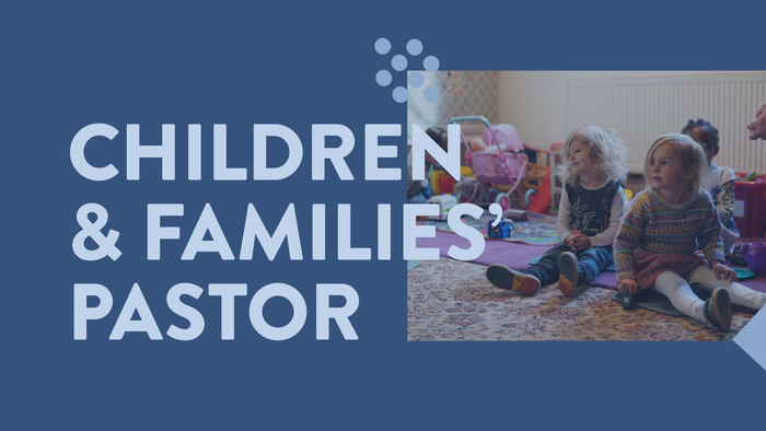 A children's pastor interacts with young kids in a cozy, play-filled indoor setting.