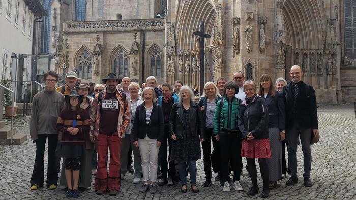 Gruppe von Menschen, die vor einer prächtigen historischen Kathedrale mit aufwendiger gotischer Architektur posieren.