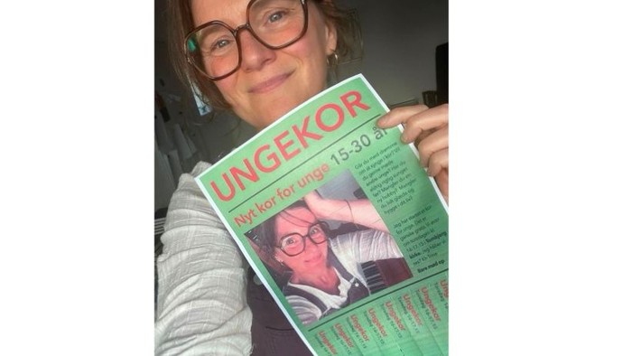 Foto af Trine Lunau med plakaten med teksten Nyt kor for unge
