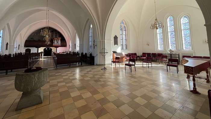 Indendørs billede af en stor, lys kirke med høje buer og høje vinduer.