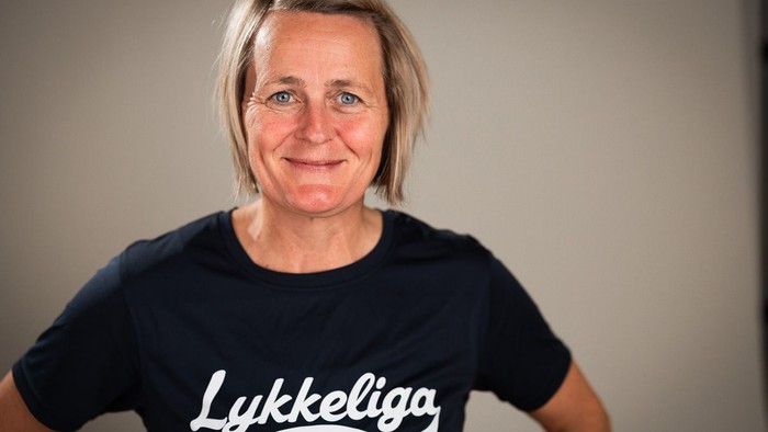 Kvinde, der smiler i en marineblå T-shirt med ordet 