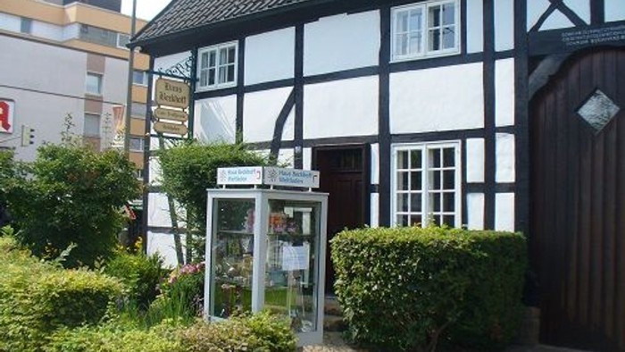 Fachwerkhaus mit Schild und Sträuchern