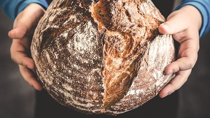 Ein Laib Brot gehalten von zwei Händen.