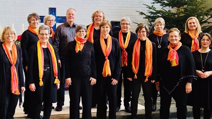 Gruppe von Personen mit aufeinander abgestimmten Schals, die gemeinsam im Freien in der Nähe eines Gebäudes posieren.