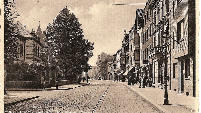 Vintage-Straßenszene in Düsseldorf mit historischen Gebäuden, Straßenbahnschienen und Architektur aus dem frühen 20. Jahrhundert.