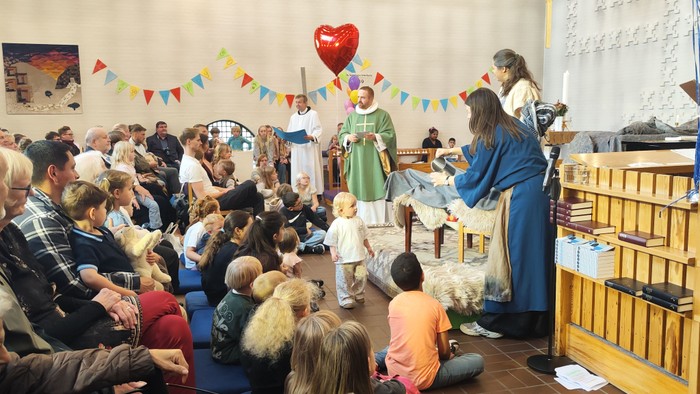 En festlig begivenhed i en kirke med børn og voksne samlet, der fejrer med dekorationer og optrædener.