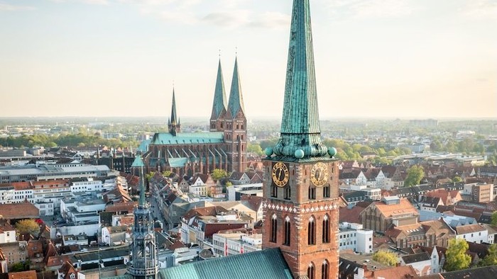 Luftaufnahme einer historischen europäischen Stadt mit einer Kathedrale mit Zwillingstürmen und bunten Dächern.