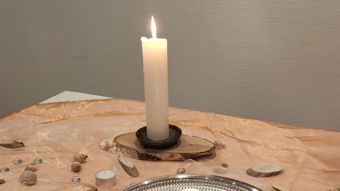 Ein Tisch mit einer Kerze und einem silbernen Tablett voller Teelichter