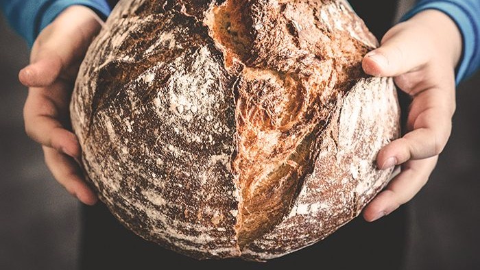 Ein Laib Brot gehalten von zwei Händen.
