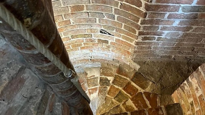 Spiralförmige Steintreppe mit Ziegelgewölbedecke und abgetretenen Stufen.