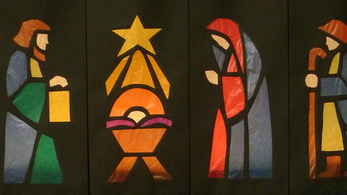 Bunte geometrische Glasmalerei-Krippe, die die Reise und Geburt Jesu mit Engeln und Figuren darstellt.