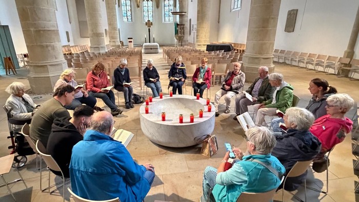 Hier sieht man eine Gruppe rund um das Taufbecken in der Christuskirche beim Friedensgebet.