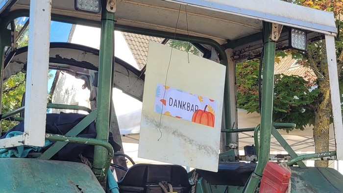 Ein grüner Traktor von hinten mit einem Schild auf dem steht