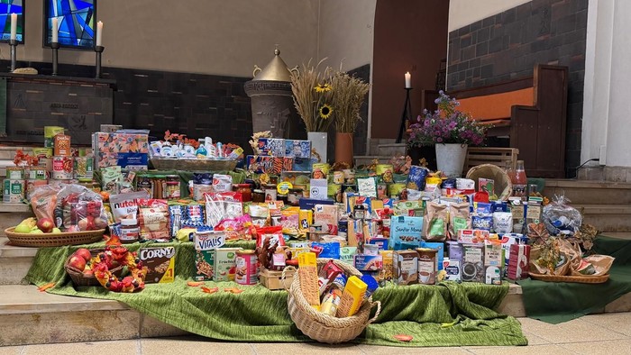 Viele Lebensmittel, Körbe und Blumen. Reiche Gaben für Bedürftige aufgestellt auf den Stufen zum Altar in der Lindenkirche
