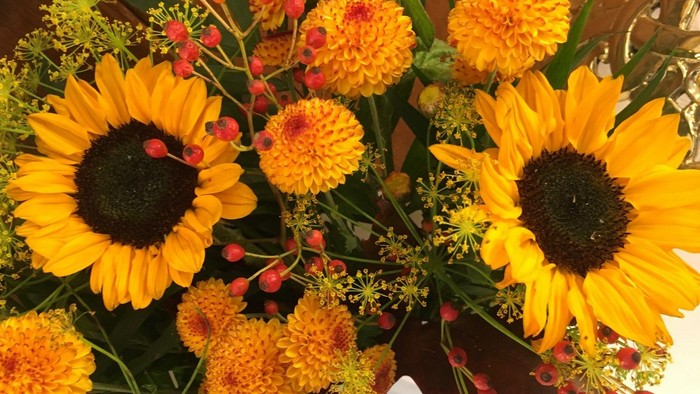 En blomsterstang med store solsikker og andre farvede blomster.