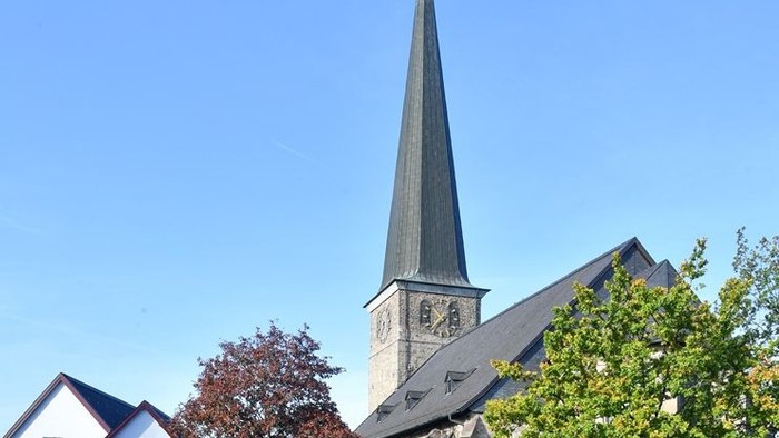 Kirche mit hohem Turm und in der Nähe geparkten Autos