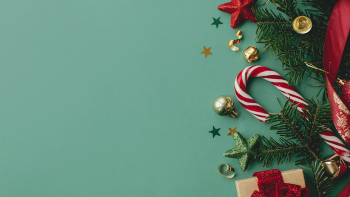 Livlige juledekorationer med slikstokke, julekugler, stjerner og en gaveæske på en festlig baggrund.