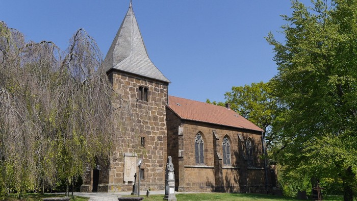 Eine kleine Kirche aus Sandstein vor blauem Himmel