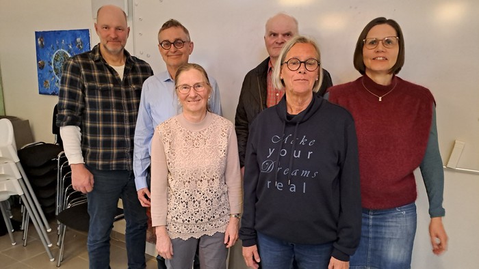 En gruppe af seks personer står sammen i et rum.