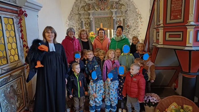 Eine Gruppe von Erwachsenen und Kindern posiert in einer historischen Kirche, einige halten blaue Luftballons.