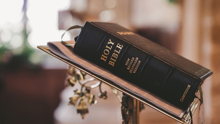 A black Holy Bible rests on a stand with a decorative cross.