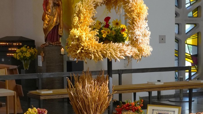 Dekorativer Altaraufbau mit Weizenarrangements, Blumen und religiösen Symbolen in einer Kircheneinrichtung.