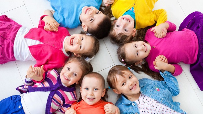 Kinder liegen lachend und spielend auf dem Boden