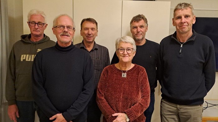 En gruppe af seks personer står sammen i et rum